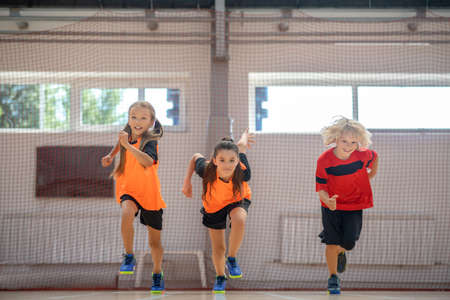 Running. Kids in bright sportswear running in the gymの写真素材