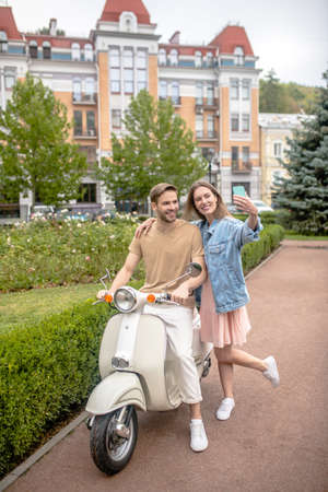 Riding a scooter. A woman taking pictures with her boyfriend and his scooterの写真素材