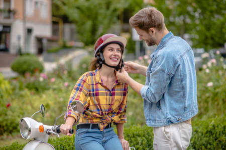 Opting for safety. A man helping a woman to wear a helmetの写真素材