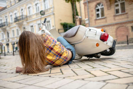 First fail. A woman laying on pawement after falling from a scooter.
