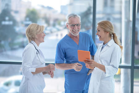 Best team. Smiling doctors studying something on tablet, having friendly conversation