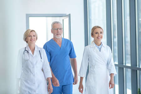 Best team. Group of smiling doctors walking along hospital hallwayの写真素材