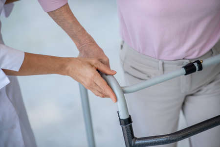 Rehabilitation. Close up of a woman with rolling-walker and a doctorの写真素材