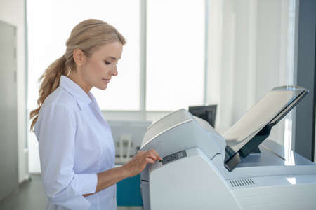 At work. Fair-haired young doctor looking busy at work