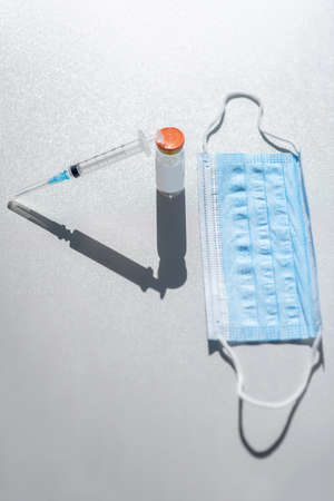 Covid-19. Protective mask, syringe and a vial on the table