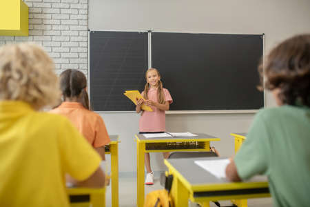At school. A girl in pink tshirt standing at the blackboard