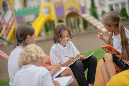 Classmates. Group of pupils sitting outside and preparing homework