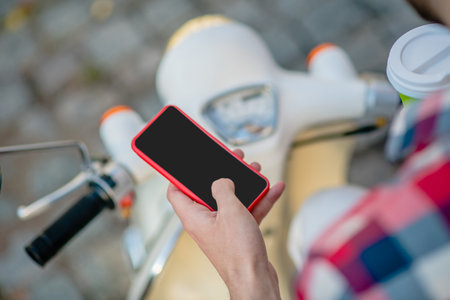 On the road. A man using a smartphone while riding a scooterの写真素材