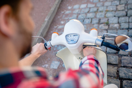 Riding fast. A man looking at his retro scooters speedometerの写真素材