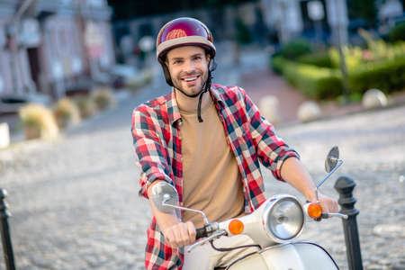 Safe ride. A man wearing a red helmet riding a scooterの写真素材