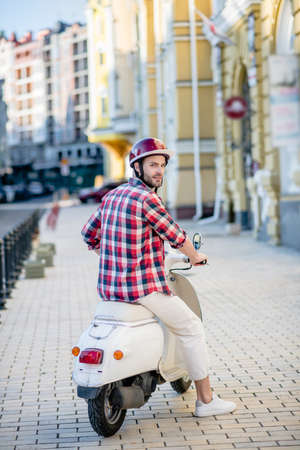 Riding thrugh the sidewalk. A man taking off on his white scooterの写真素材