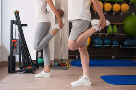 Stretching legs. A man and a woman in white sneakers stretching their legs