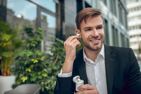 Wireless headphones. Handsome man wearing wireless headphones and looking contentedの写真素材