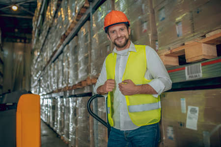 Contented smile. Young male worker standing near shelves and looking contentedの写真素材