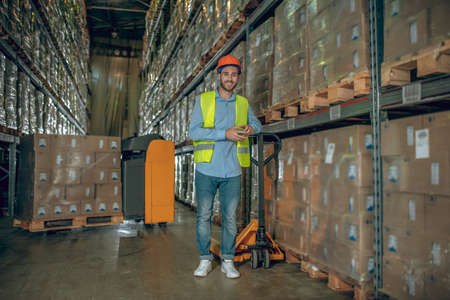 Full of energy. Young male worker standing near the loader and smilingの写真素材