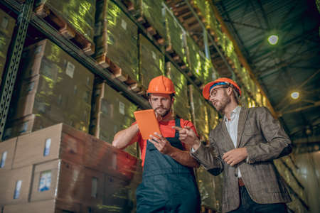 Correct data. Warehouse worker and manager checking the data online and looking serious