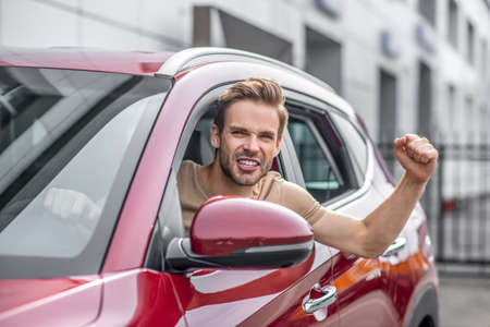 Car driving. Excited male driving car, raising hand in the airの写真素材