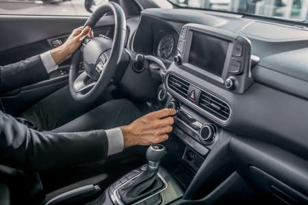 Drive test. Close-up of male hands holding steering wheel, pressing control buttons