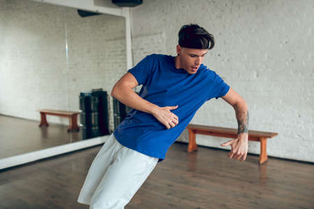 Dancing experience. A concentrated man performing an isolation movement while dancing