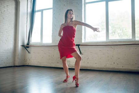 Dance class. A professional dancer wearing red dress during the rehearsalの写真素材