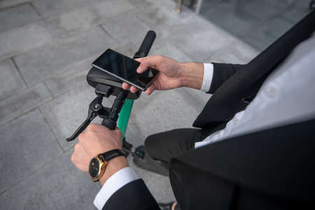 Devices. Close up picture of mans hands holding a handle bar and smartphone