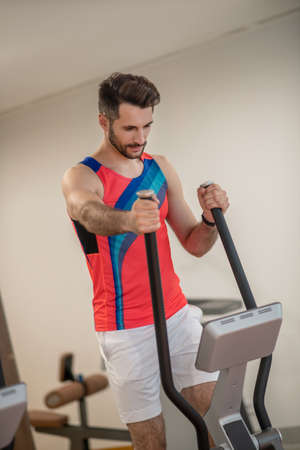 Determined. Young dark-haired man exercising in gym and looking determined