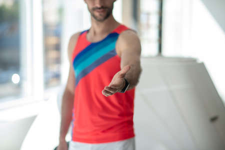 Invitation. Sporty man in bright tshirt outstretching his armの写真素材