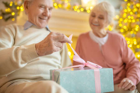 Gift. Elderly man opening christmas gift from his wife and looking happyの写真素材