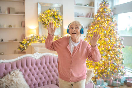 Good mood. Senior woman listening music in headphones and dancing