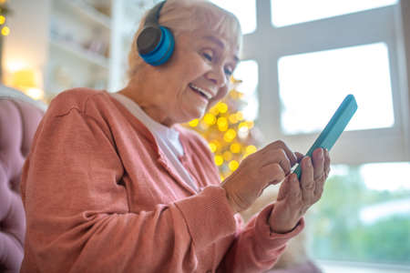 Online. Smiling woman holding a smartphone and watching something onlineの写真素材