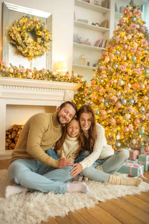 Happy christmas. Smiling happy family sitting on the floor near christmas treeの写真素材