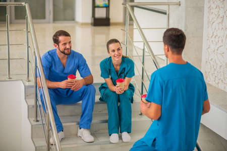 Coffee break. Medical workers sitting on the stairs and having coffee breakの写真素材