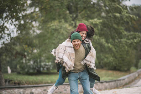 Playful mood. A man carrying a woman on his back