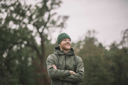 Waiting. Young man in a green coat standing in the parkの写真素材