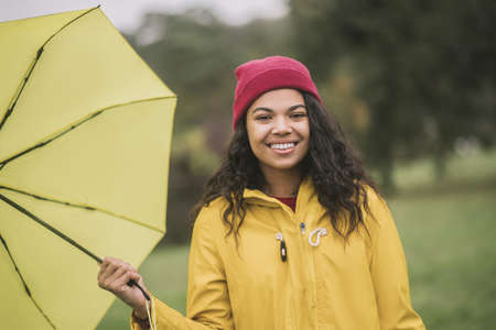 Happy smile. Cute mulatta with yellow umbrella feeling happy