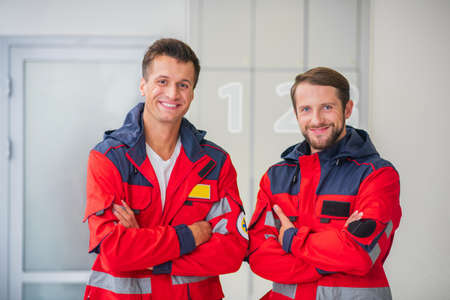 Medical crew. Two medical workers in red uniform smiling and feeling confidentの写真素材