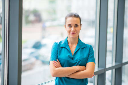 Female doctor. Pretty young female doctor in blue uniform smiling nicelyの写真素材