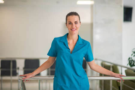 At work. Young female doctor in blue uniform standing at the stairsの写真素材