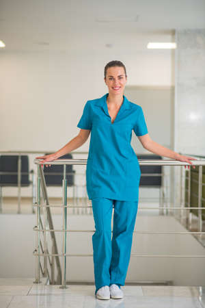 At work. Young female doctor in blue uniform standing at the stairsの写真素材