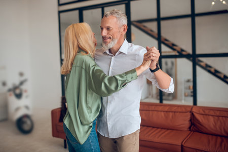 Good mood. Man and woman dancing in the room and looking enjoyedの写真素材