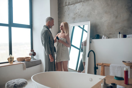 Man in bath robe and blonde woman in towel looking at each other with loveの写真素材