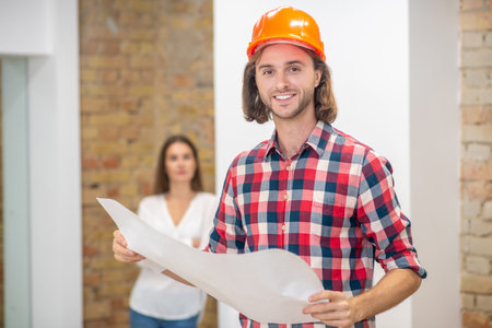 Project design. Young man in protective helmet holding the project design