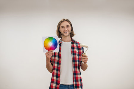 Painting. Young man holding a paint roller and a color paletteの写真素材