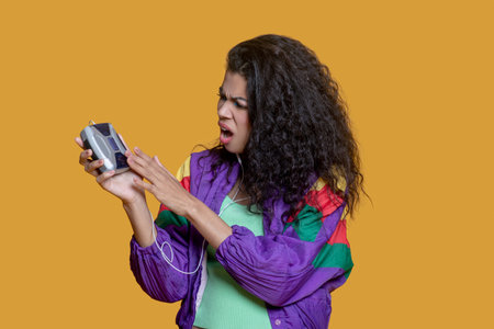 Confused. Cute dark-haired young girl with an old music player feeling confusedの写真素材