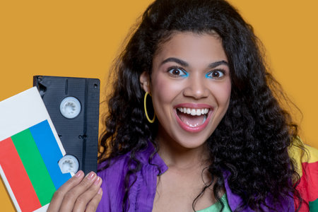 Retro. Pretty dark-haired young girl with video cassette looking happy