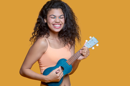 Cute girl. Pretty dark-haired young girl in yellow clothes with ukulele