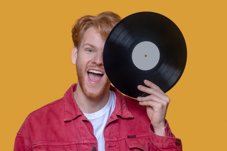 Young man. Red-haired bearded young guy in red jacket with a recordの写真素材