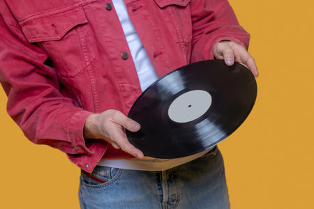 Music lover. Man in red jacket holding a record in hand