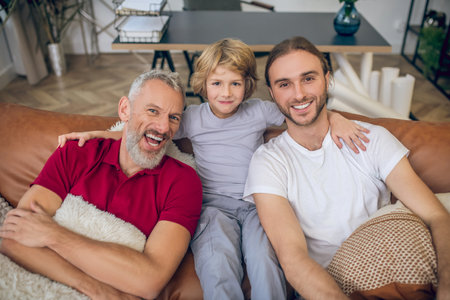 Happy family. Cute blonde boy and two men having good time together