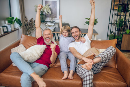 Happy family. Cute blonde boy and two men having good time together and looking happyの写真素材